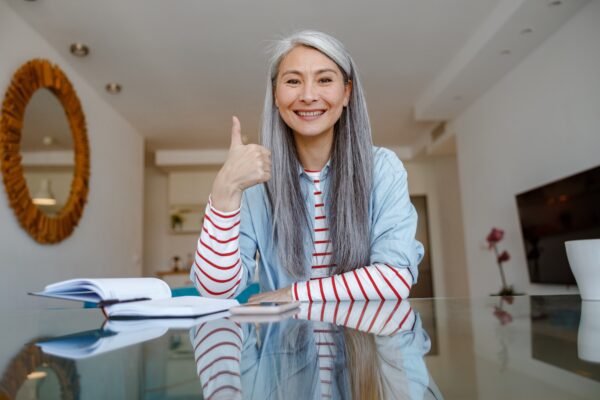 Joyful woman doing thumbs up gesture at home