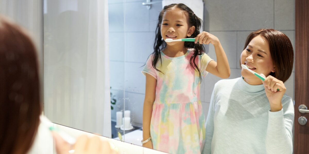 Mother and daughter brushing teeth Book and appointment with TranscenDental Smiles for your tooth extraction