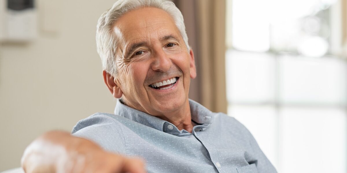 Senior man smiling at home TranscenDental Smiles is a great dentist to see about porcelain veneers.