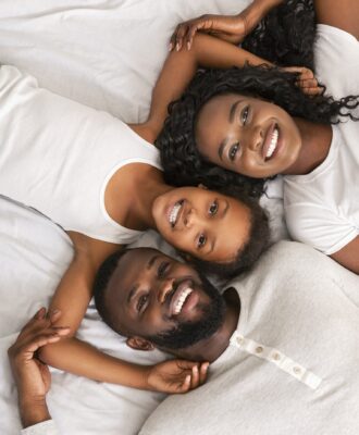 Top view of happy black family lying in bed together Top view of happy black family lying in bed together