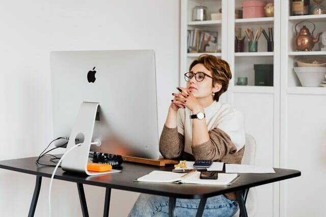 A woman sitting at a desk with a computer, working on a template.